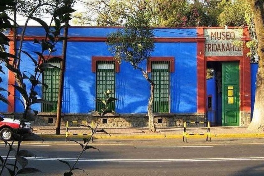 A building with a blue facade, green doors, and a sign that reads 'MUSEO FRIDA KAHLO'. 5