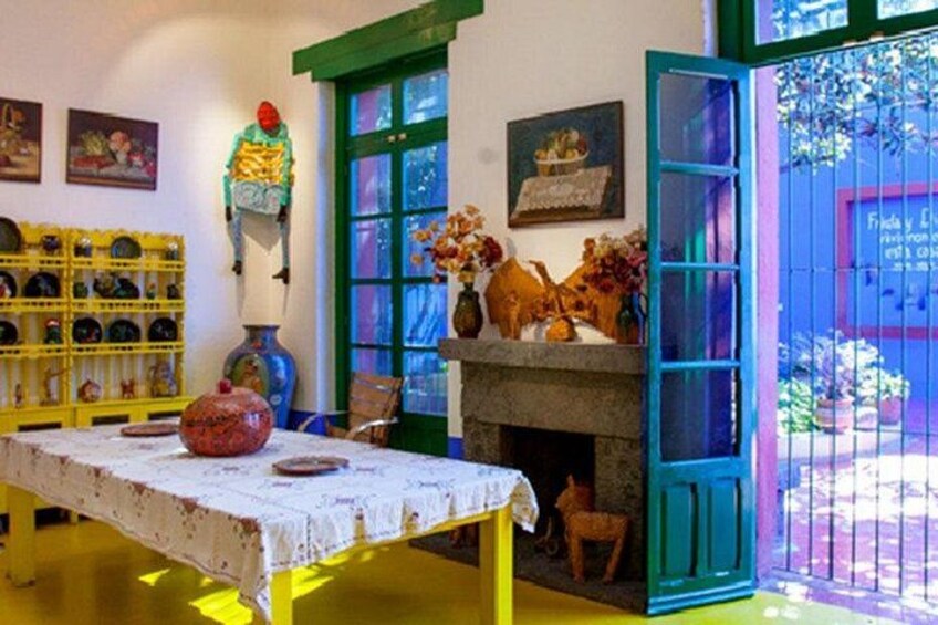 A room with a table, chairs, a fireplace, and a colorful door. 2