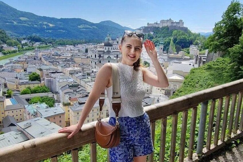 A person standing on a balcony overlooking a city with a castle in the background. 2