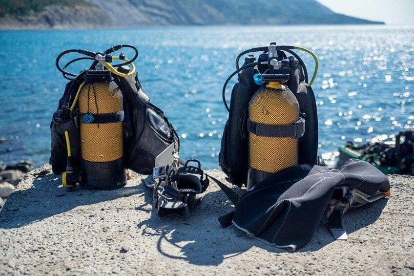 Two scuba diving tanks on a rocky shore with the ocean in the background. 4