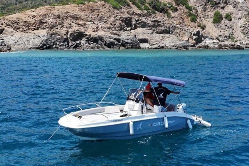A small motorboat with a canopy on the water near rocky cliffs. 3