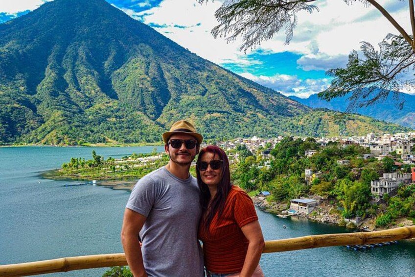 A couple standing by a lake with mountains in the background. 2