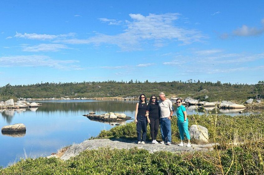 Un grupo de personas sobre un saliente rocoso junto a un lago tranquilo con una orilla boscosa al fondo. 2