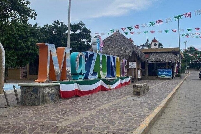 A colorful sign with the word 'MOZAMBIQUE' and a thatched-roof building in the background. 4
