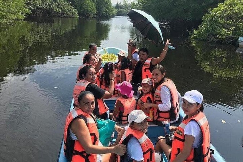 A group of people on a boat wearing life jackets, surrounded by water and greenery. 1