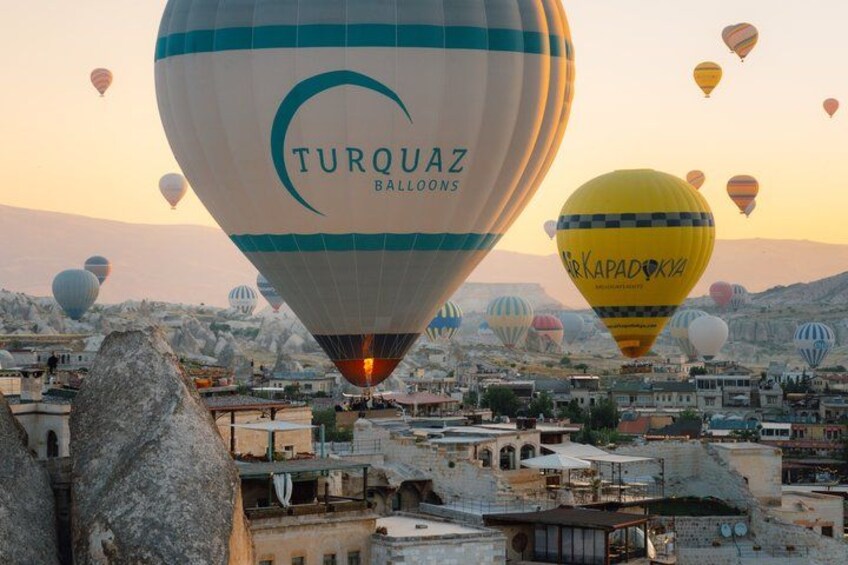 A cityscape with multiple hot air balloons, including one with 'TURQUAZ BALLOONS' branding. 1