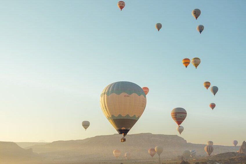 Un gruppo di mongolfiere nel cielo sopra un paesaggio desertico. 2