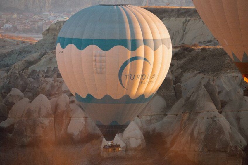 A hot air balloon with 'Turquois' written on it, flying over a rocky landscape. 3