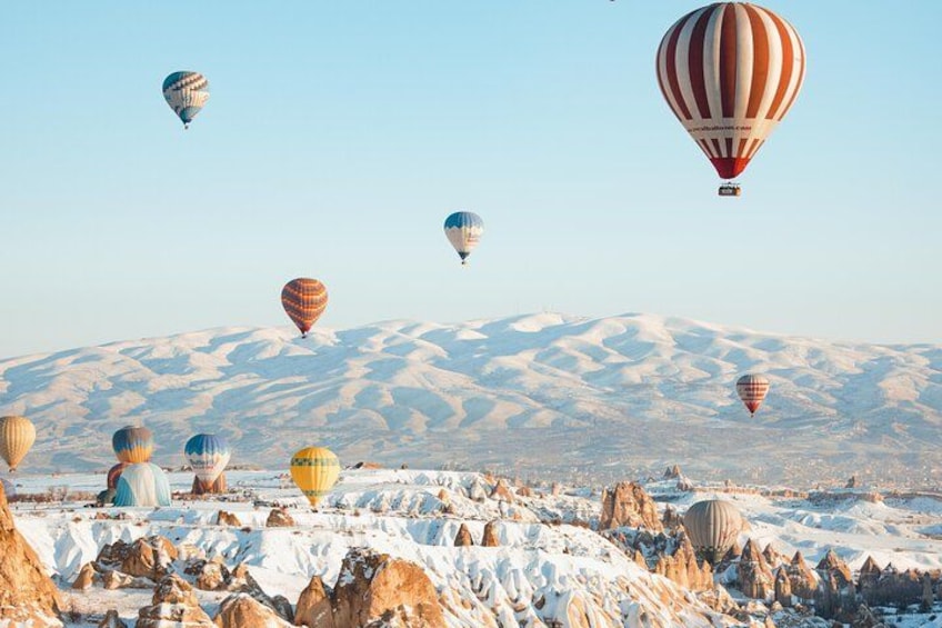 Hot air balloons over a snowy landscape with rocky formations. 3