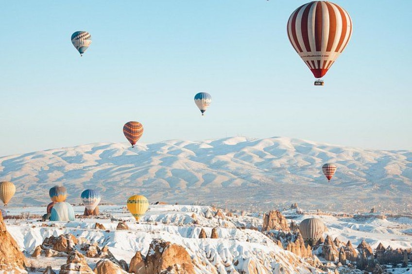 Hot air balloons over a snowy landscape with mountains in the background. 2