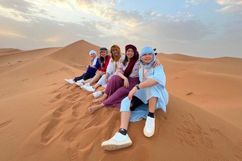 Un grupo de personas sentadas sobre una duna de arena en un paisaje desértico. 2