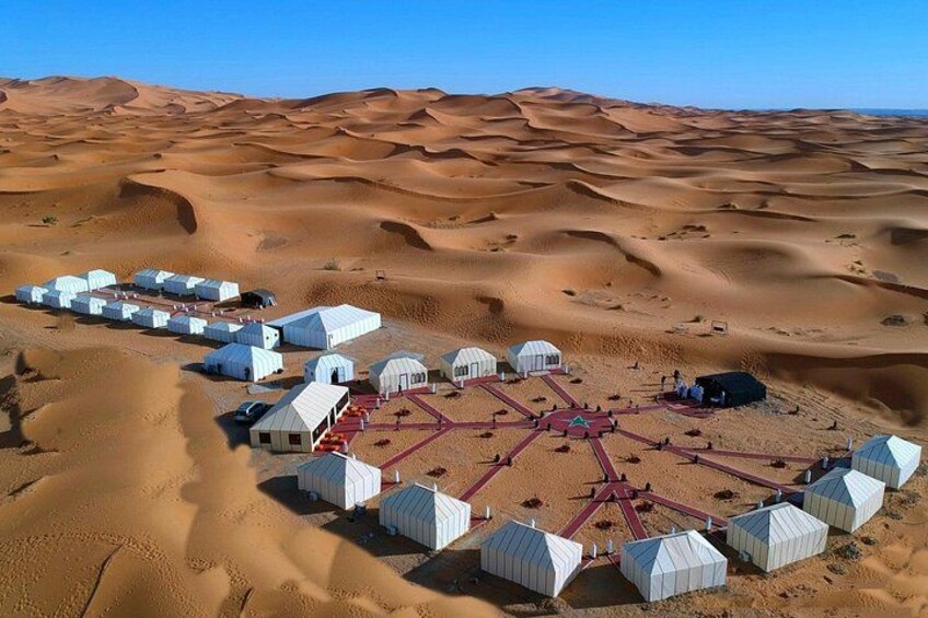 Un campement dans le désert, composé de tentes et d’une structure centrale. 1