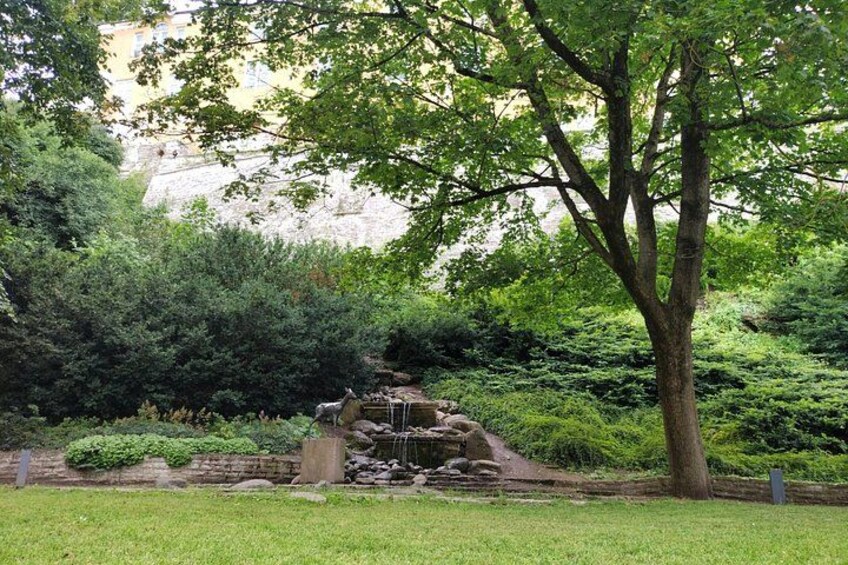 Ein Park mit einem Wasserfall, Bäumen und einer Steinmauer. 4