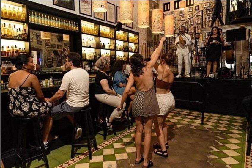 Un bar con clientes, un escenario con una banda y un suelo estampado. 2