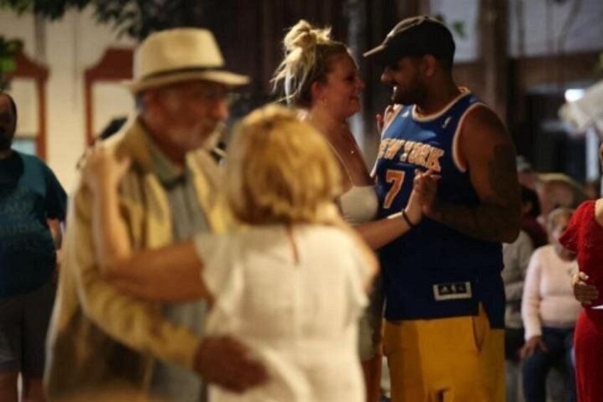Un jugador de baloncesto con la camiseta de los New York Knicks, una mujer con una blusa blanca y un hombre con sombrero. 5