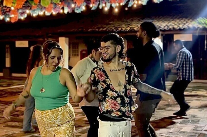 Una persona con una camicia floreale balla con un'altra persona in una maglia verde. 4