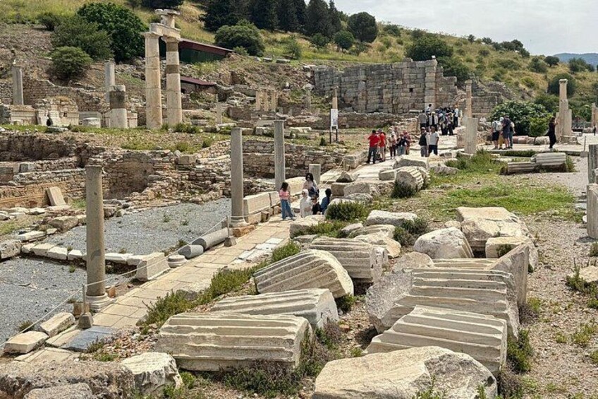 Ancient ruins with stone columns and steps, surrounded by tourists. 4