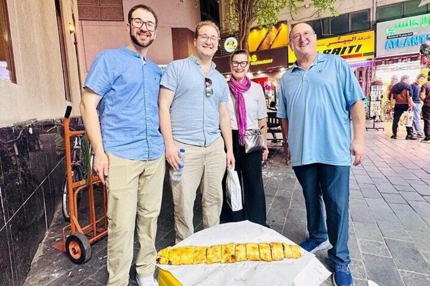 Quatre personnes se tiennent sur un trottoir, à côté d’un chariot et d’un grand objet jaune posé sur le sol. 2