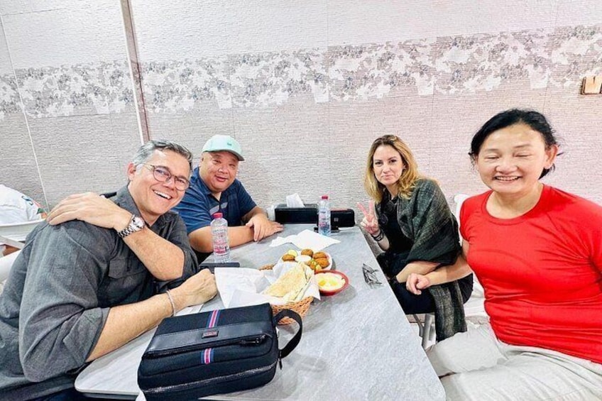 Un groupe de personnes est assis autour d’une table, devant de la nourriture et des boissons. 5