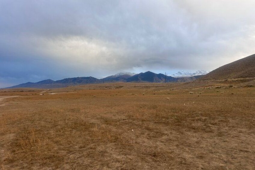 Una pradera seca con montañas al fondo bajo un cielo nublado. 3