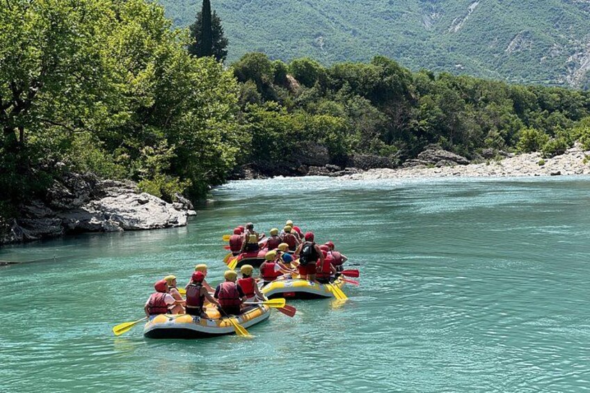 A group of people rafting down a river surrounded by lush greenery and rocky terrain. 5