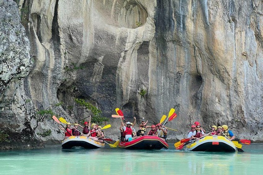 A group of people kayaking in a narrow waterway with rocky cliffs in the background. 2