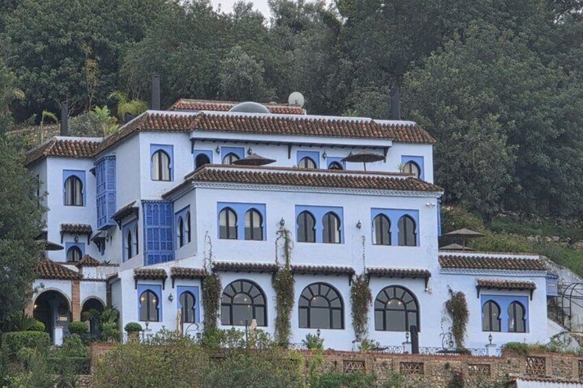 Un edificio de varios pisos con paredes azules y blancas, ventanas arqueadas y techo de tejas. 5