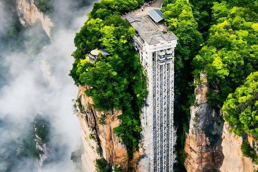 A tall tower with a flat top, surrounded by dense green foliage and cliffs. 5