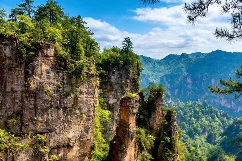 A mountainous landscape with prominent rock formations and dense forest. 3