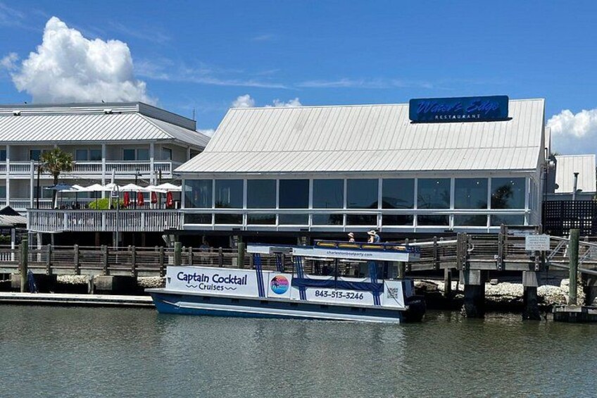 A waterfront restaurant with a boat docked in front. 1