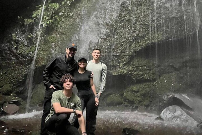 A group of people in a forested area with a waterfall. 4