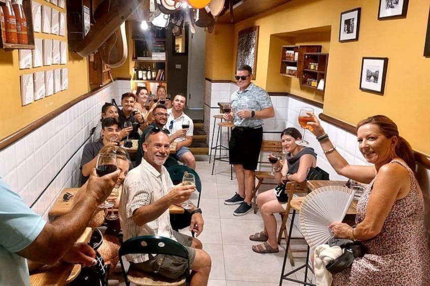 Un grupo de personas en un restaurante, algunas sosteniendo bebidas, con un bartender detrás. 5