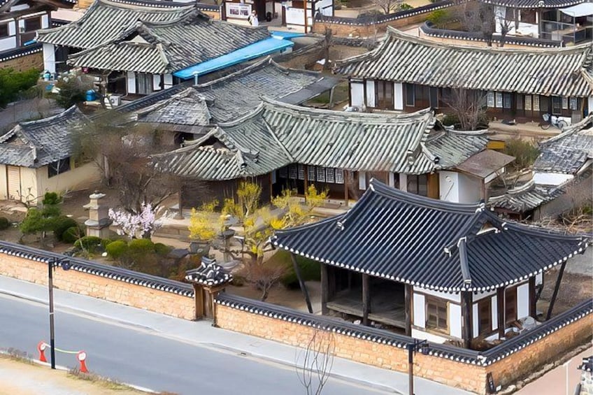 A traditional Korean village with ornate rooftops and a well-maintained garden. 2