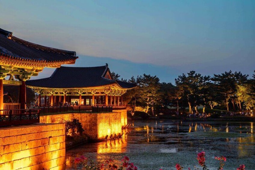 A traditional Korean pavilion with a tiled roof, a stone bridge, and a pond with lotus flowers. 5