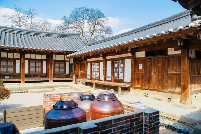 A traditional Korean building with wooden architecture and large ceramic pots. 2