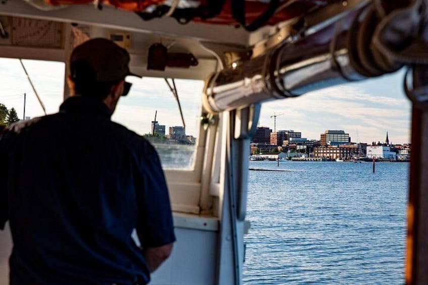 A man on a boat, water, and a city skyline in the background. 3