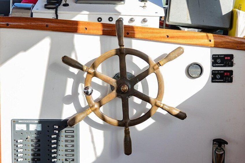 A ship's wheel, control panel, and wooden trim. 4