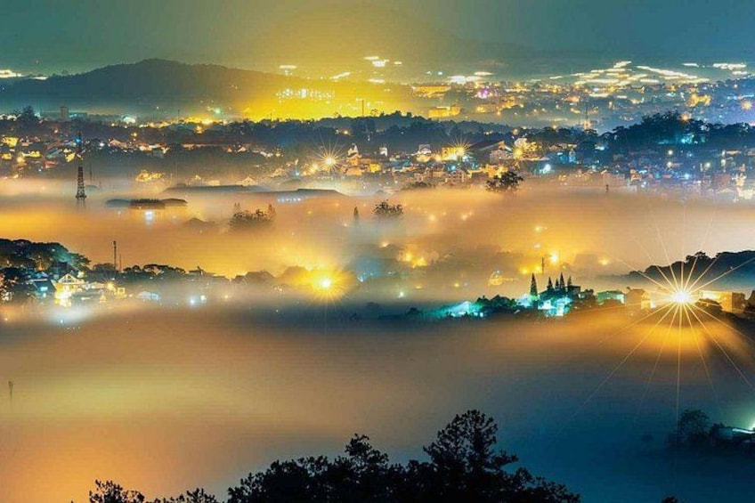 A cityscape at night with illuminated buildings and a foggy atmosphere. 2