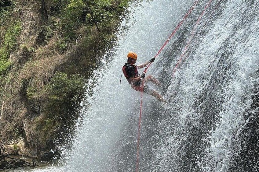 A person rappelling down a waterfall. 4