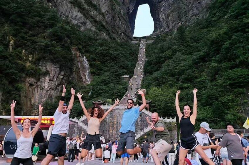 Eine Gruppe von Menschen feiert vor einer großen Felsformation mit einem natürlichen Bogen. 4