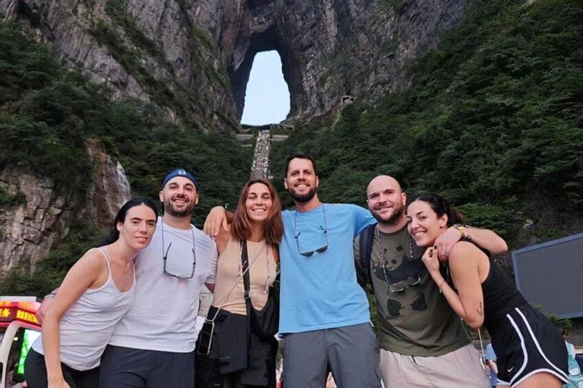 Eine Gruppe von Menschen posiert vor einer felsigen Klippe mit einer hohlen Öffnung. 5