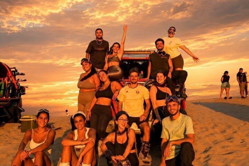 Un grupo de personas en una playa con un atardecer de fondo. 5