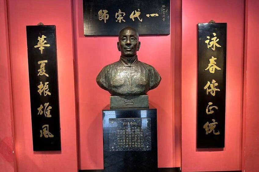 A bust sculpture with inscriptions on a red wall. 2