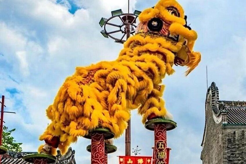 A traditional lion dance with a bright yellow costume, set against a backdrop of traditional architecture and a clear sky. 4