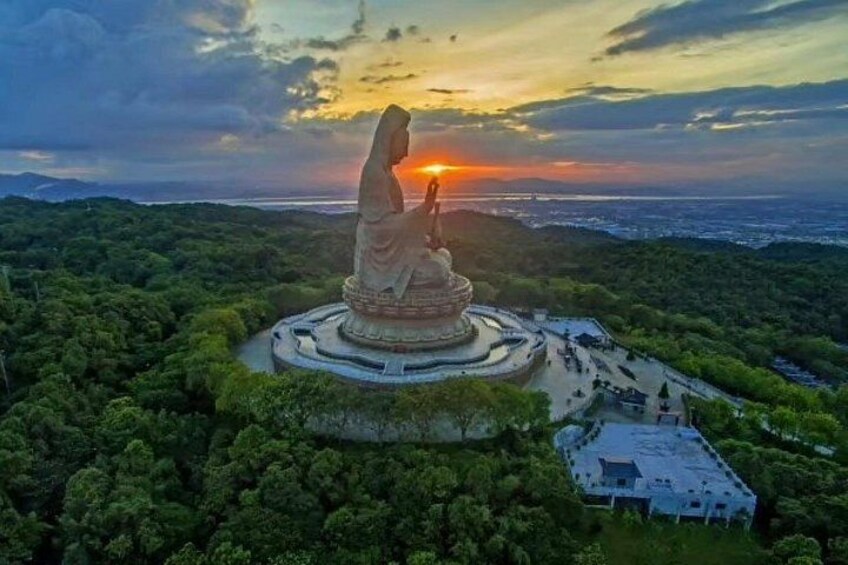A large statue on a hill with a sunset in the background. 1