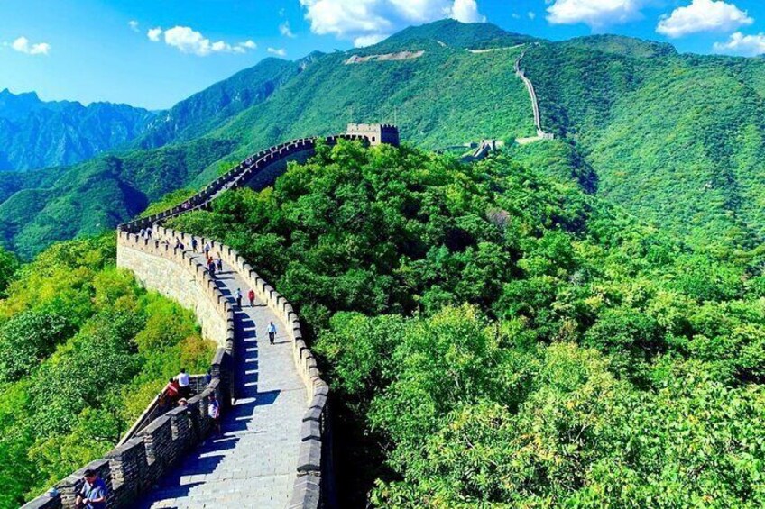The Great Wall of China winding through lush green mountains. 4