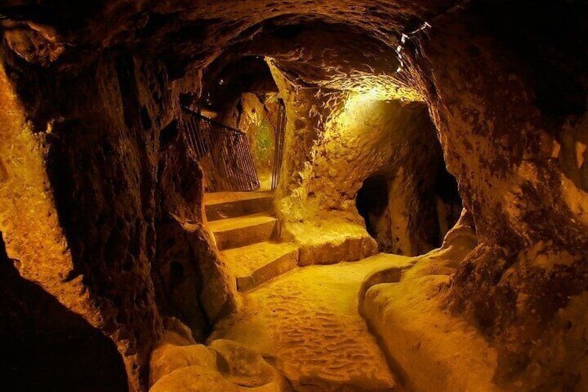 Un escalier en pierre à demi éclairé, situé dans une grotte aux murs bruts et orné d’une rambarde en bois. 2