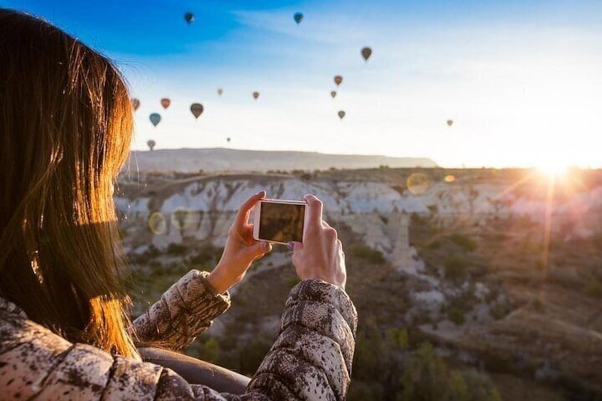Une personne prend une photo de montgolfières dans un paysage montagneux. 4