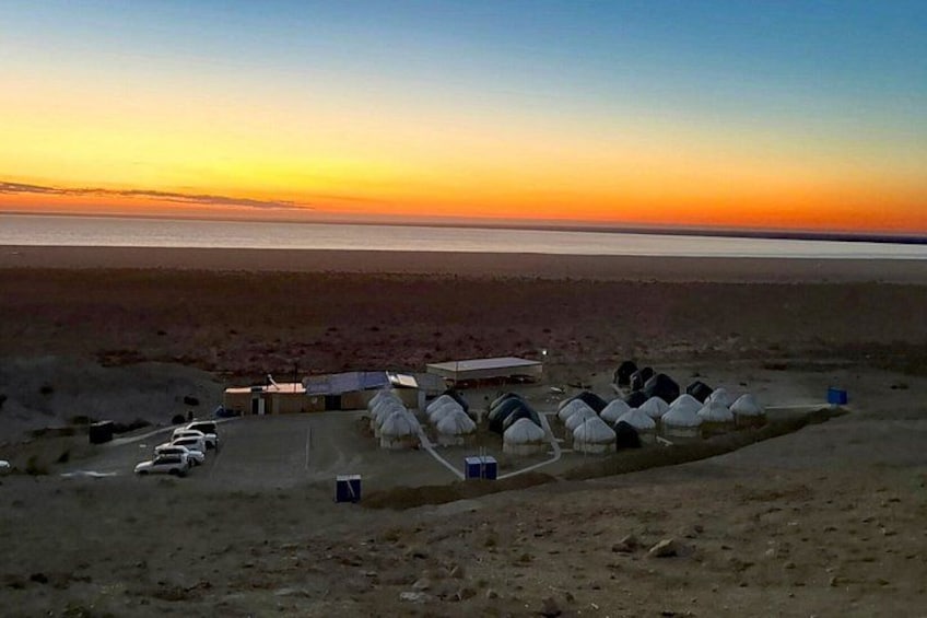 Et ørkenlandskab med yurts og en strand ved solnedgang. 1