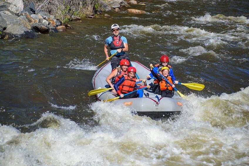 A group of people in a raft navigating a river with rapids. 2